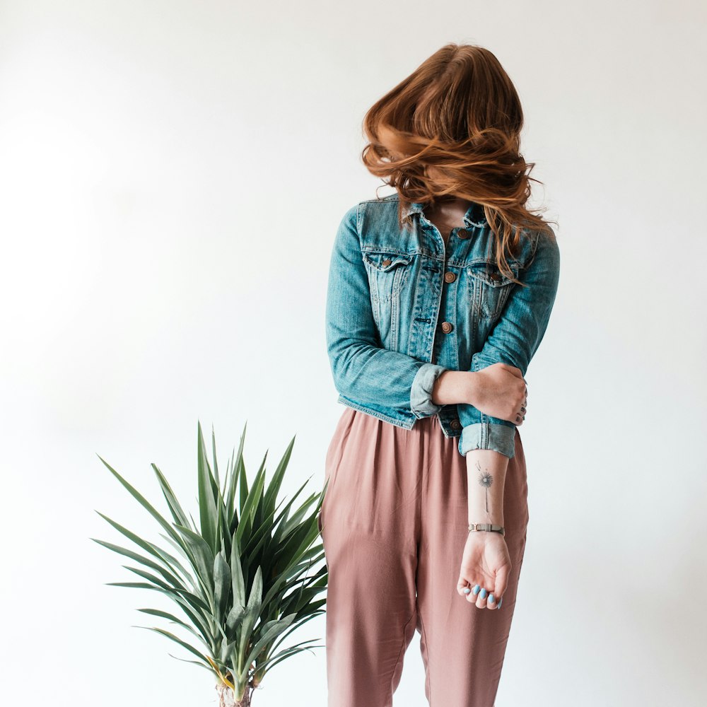 a woman standing next to a potted plant