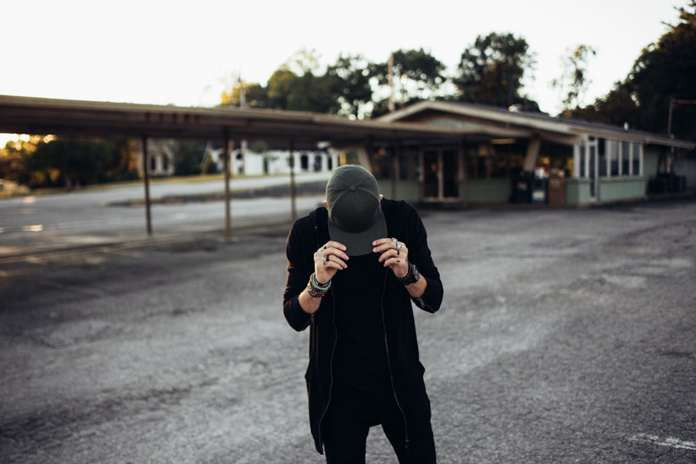 a man standing in the middle of a road holding a hat