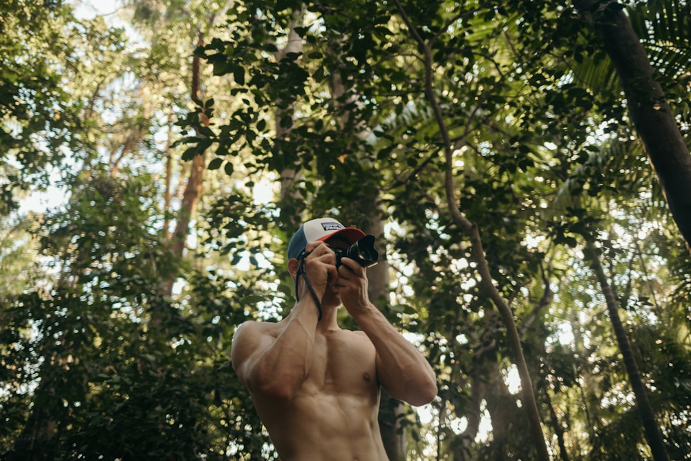 a shirtless man taking a selfie in the woods