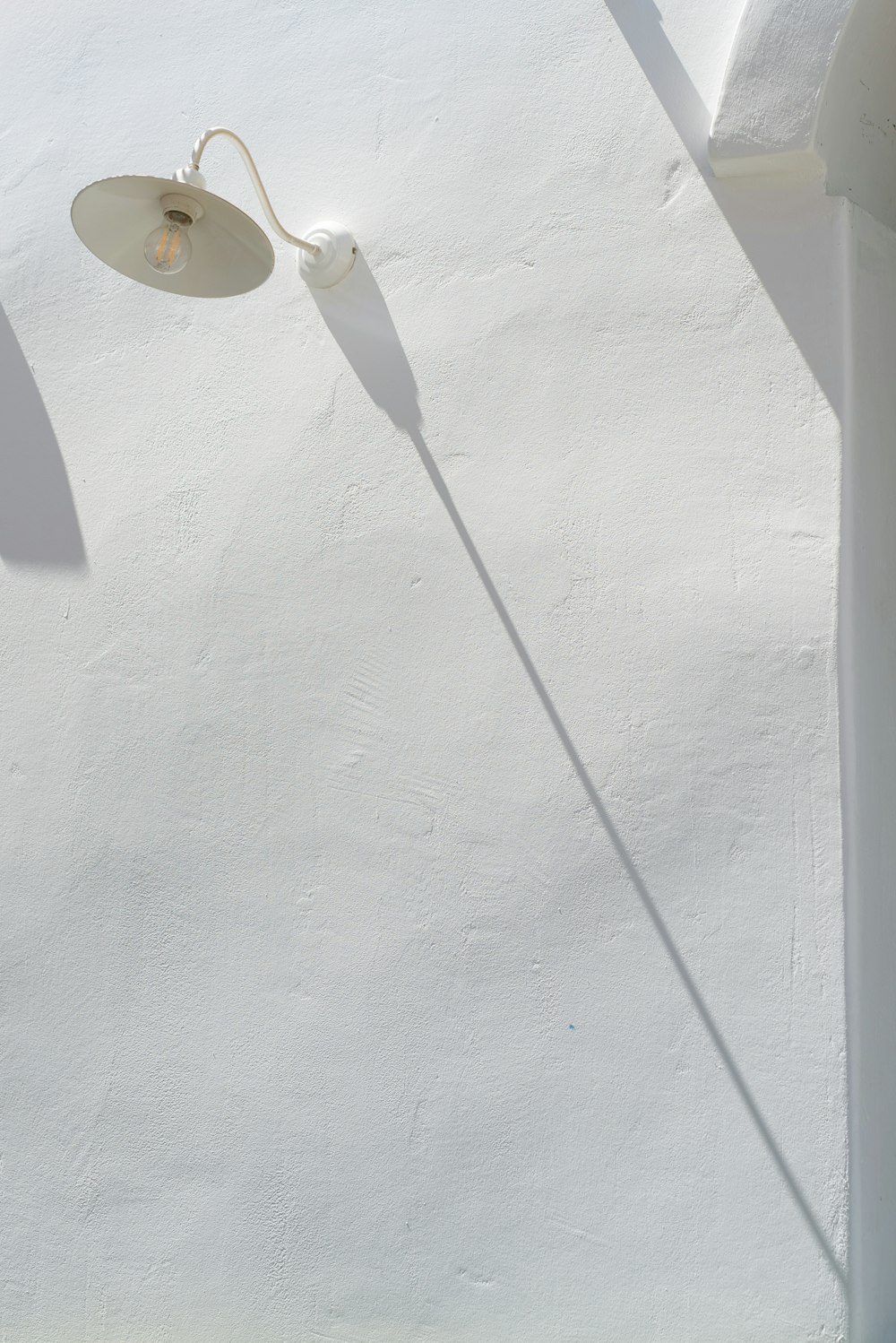 a white wall with a lamp on top of it