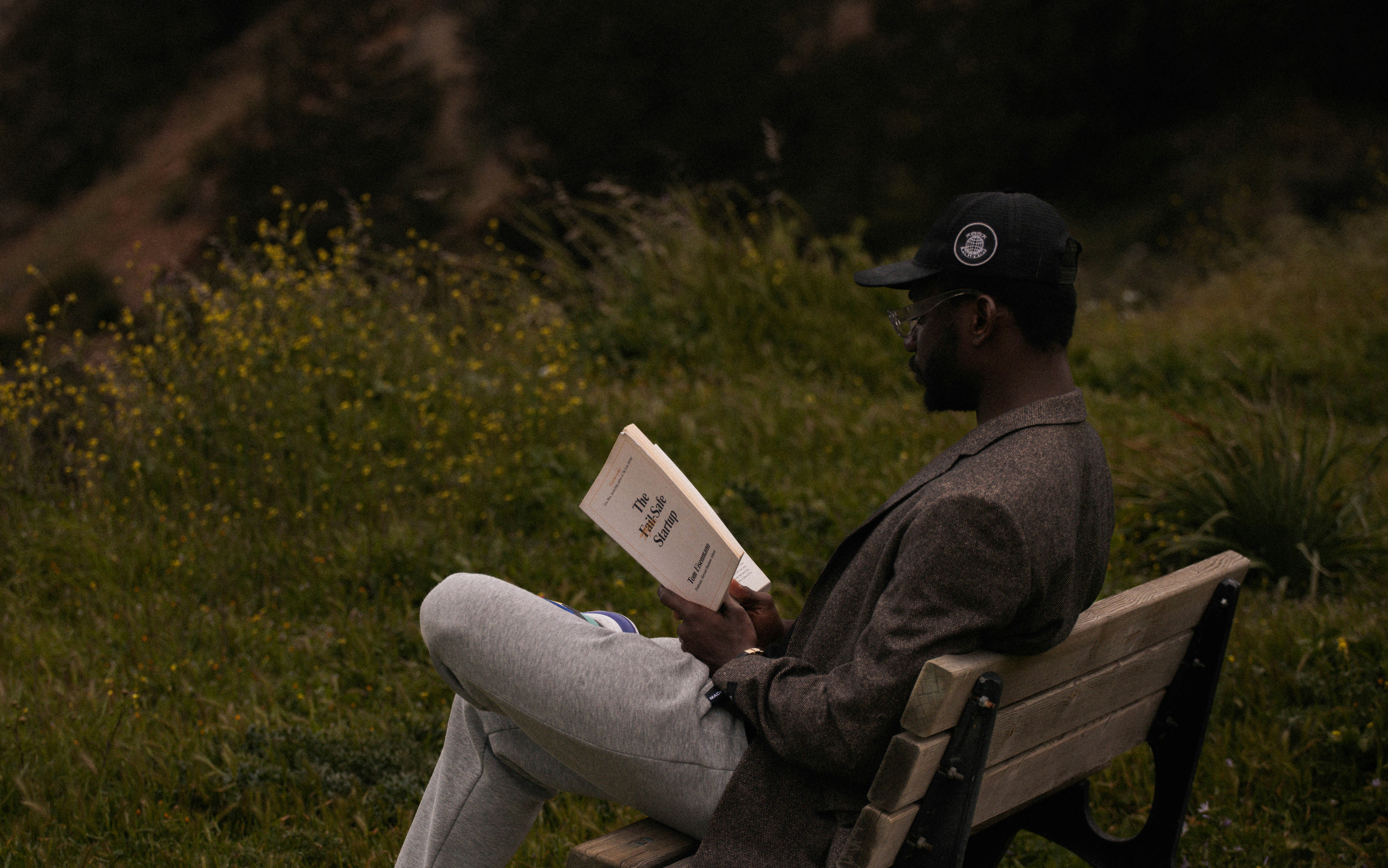 a man sitting on a bench reading a book