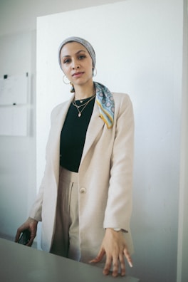 Model walking confidently in a tailored beige blazer paired with minimalist accessories.