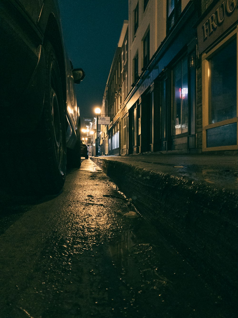 Una strada bagnata di notte con auto parcheggiate sul lato