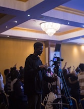 a man standing next to a camera in front of a crowd of people