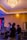 Two people are using professional video equipment in a venue with a large chandelier and various technical equipment around. The setting suggests preparation or coverage for an event.