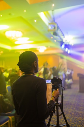 A videographer setting up a camera in a bright, modern conference room ready for a deposition.