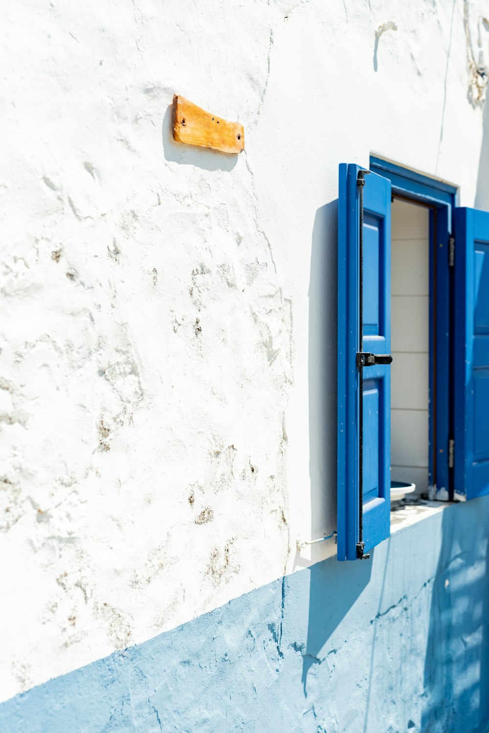 a white building with blue shutters and a wooden door