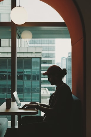 Photo of Bharat, the founder, working on a laptop with a modern Jaipur cityscape softly blurred behind.
