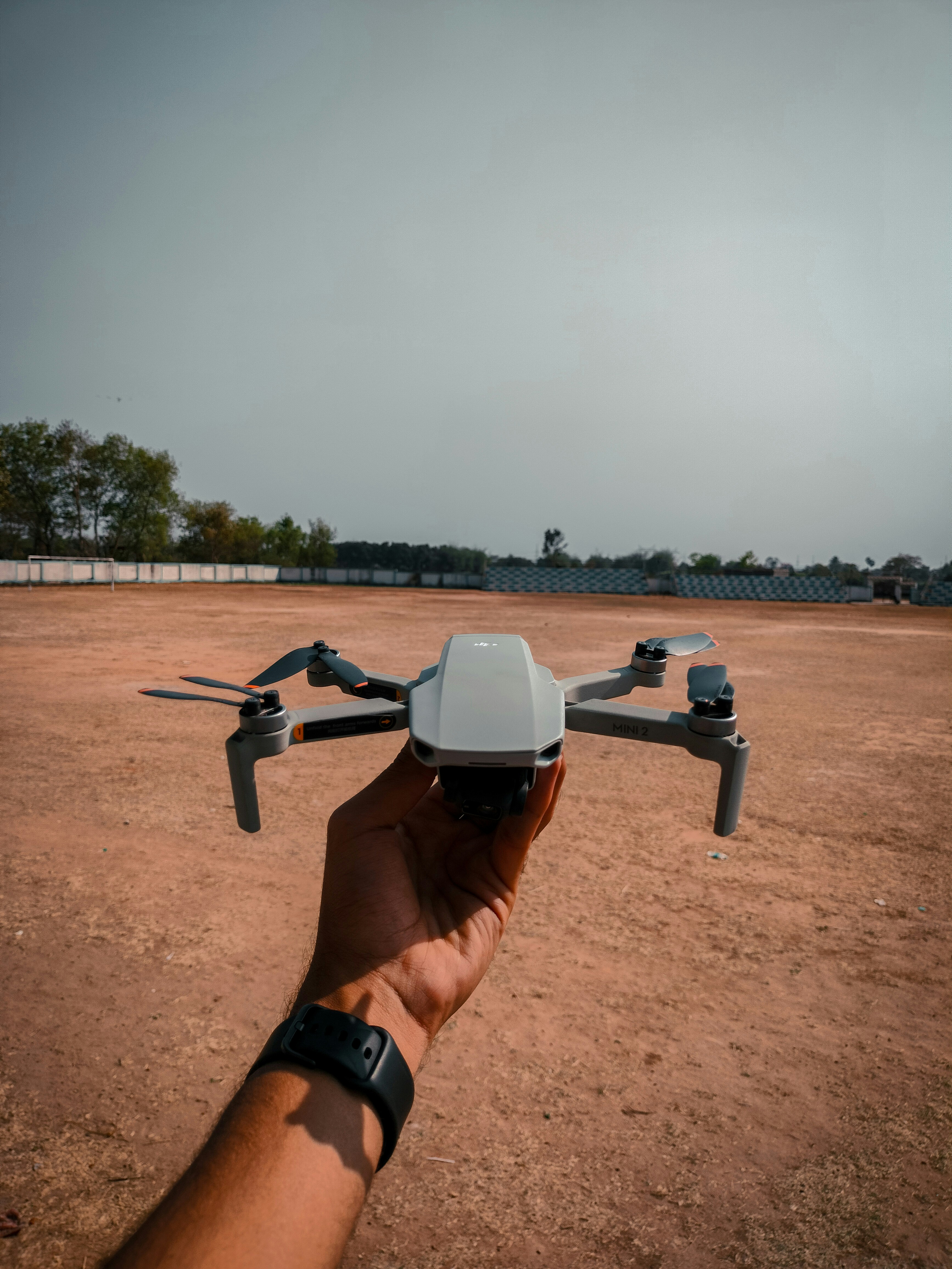 DJI drone on open hand against blue sky, outdoor setting, bright sunlight
