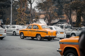 A busy street in Kuwait with a yellow taxi from Taksi Al-Hawari navigating through traffic smoothly.