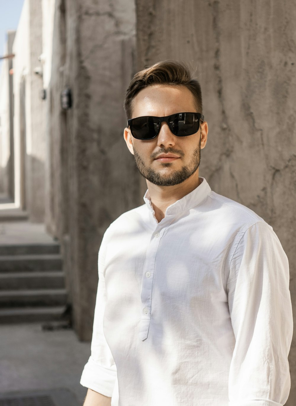 a man wearing sunglasses standing in front of a building