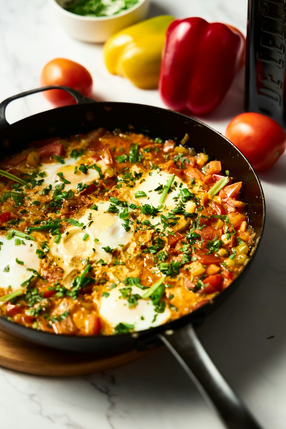 a skillet with eggs and tomatoes on a table