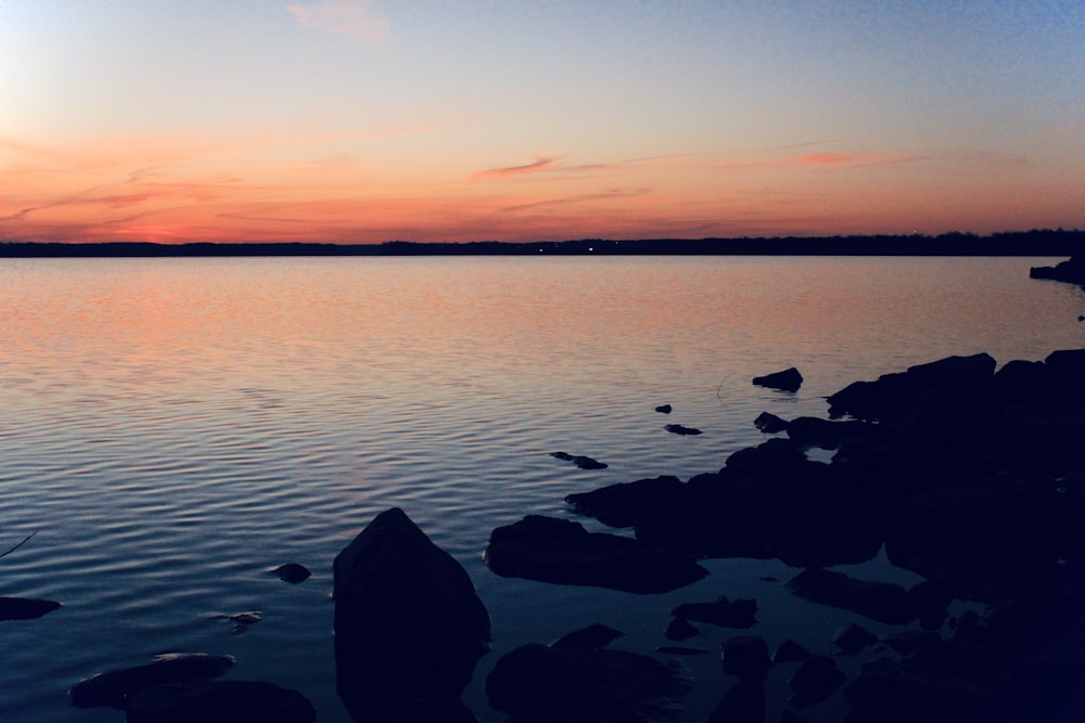 a body of water with rocks in the foreground