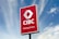 A large outdoor sign with a red background displaying the logo and text of a banking center, set against a partly cloudy blue sky.