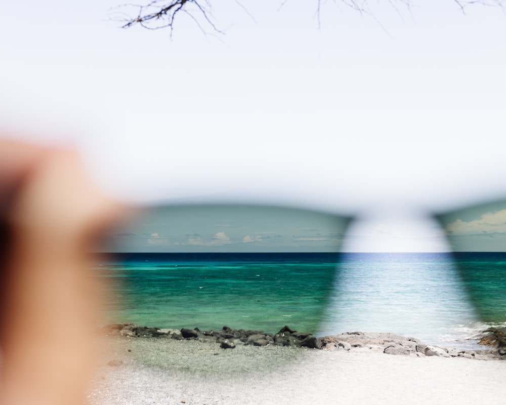 a pair of sunglasses sitting on top of a sandy beach