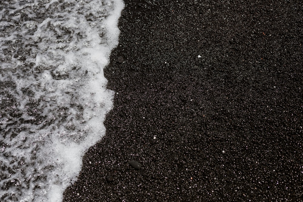 a black sand beach with a wave coming in