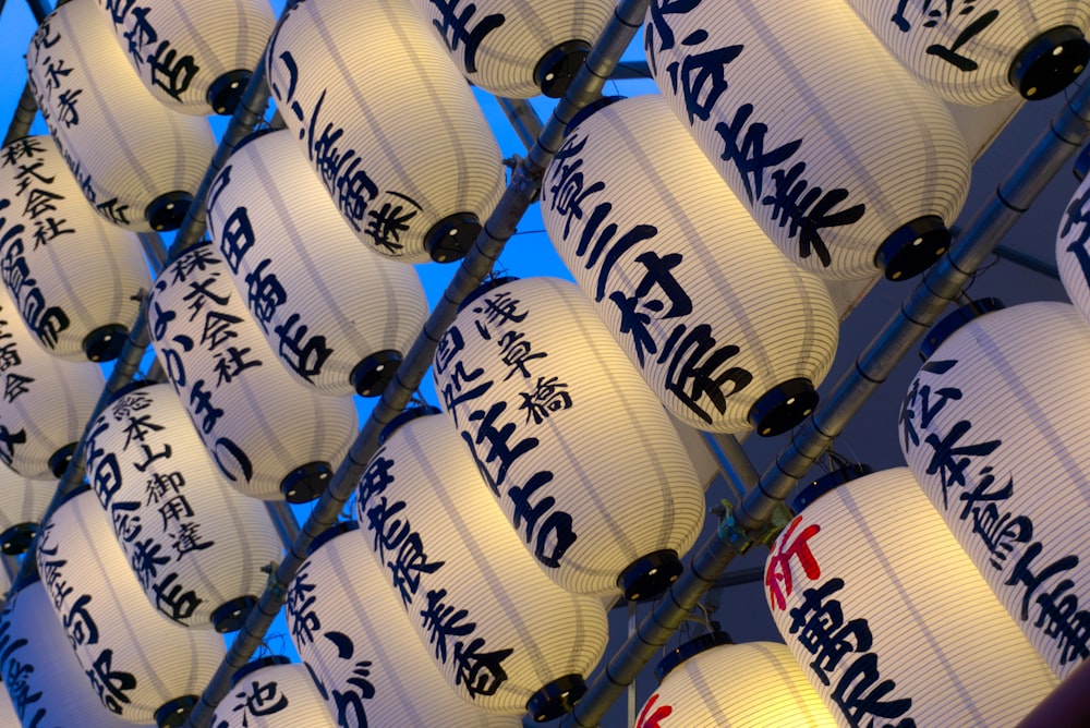 a bunch of white paper lanterns with writing on them