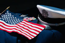 U.S. flag beside a military dress uniform, service cap, and medals