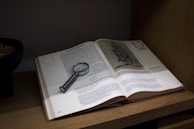 an open book with a magnifying glass on top of it