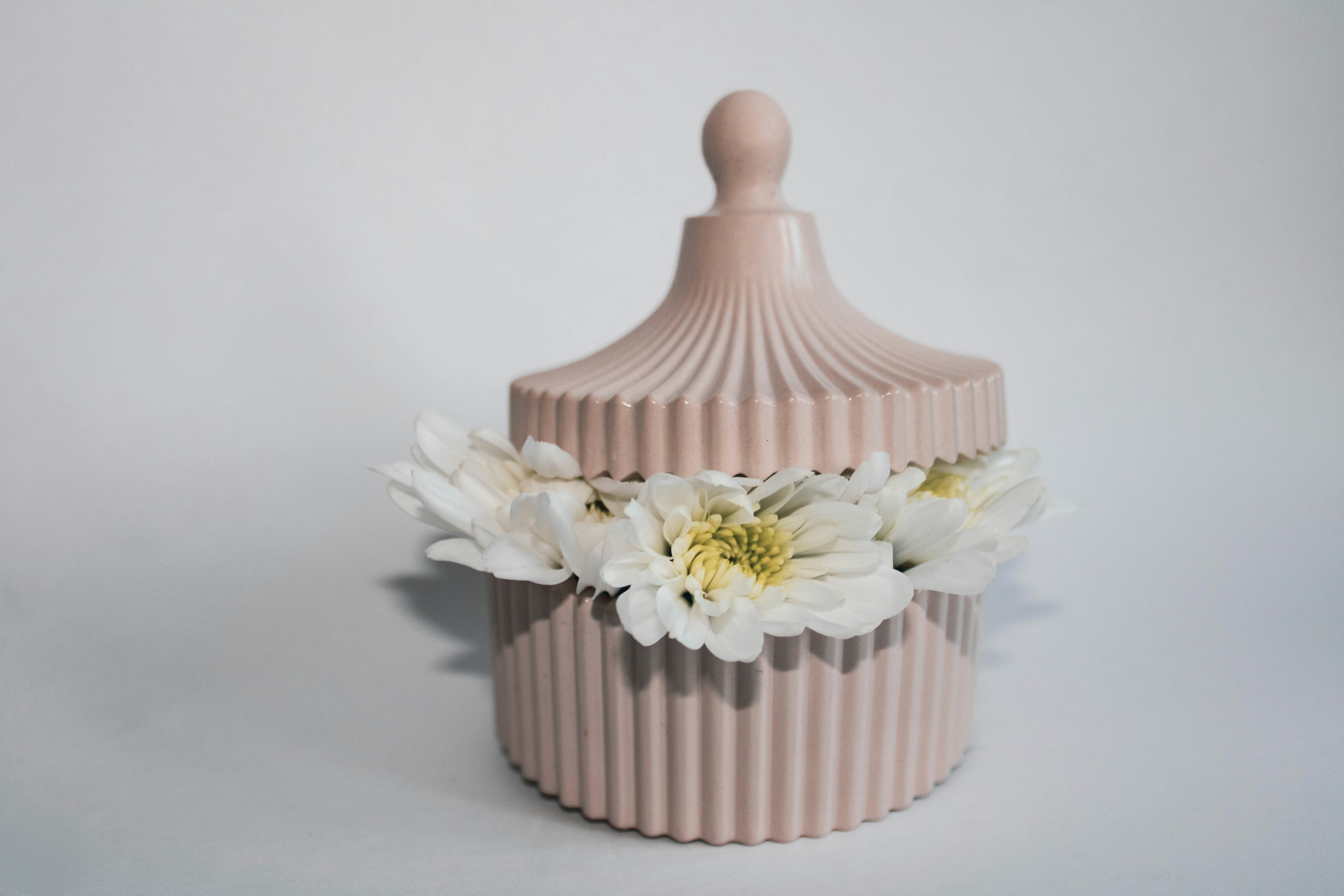 eine rosa Vase mit weißen Blumen darin