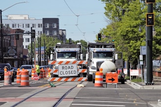 A busy city street with multiple lanes closed off, crews in high-visibility gear directing traffic safely.
