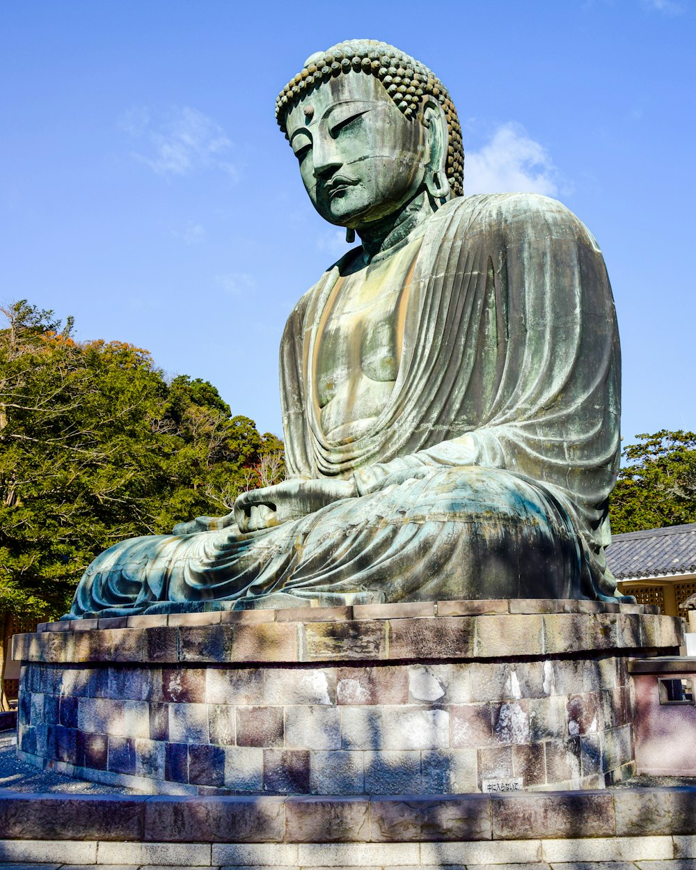 a large buddha statue sitting on top of a stone wall