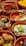 Various earthenware dishes filled with an assortment of Middle Eastern or Mediterranean foods including sliced tomatoes and cucumbers, falafel, creamy dips with herbs, olives, and pickles. Each dish is arranged attractively with garnishes of mint and other herbs.