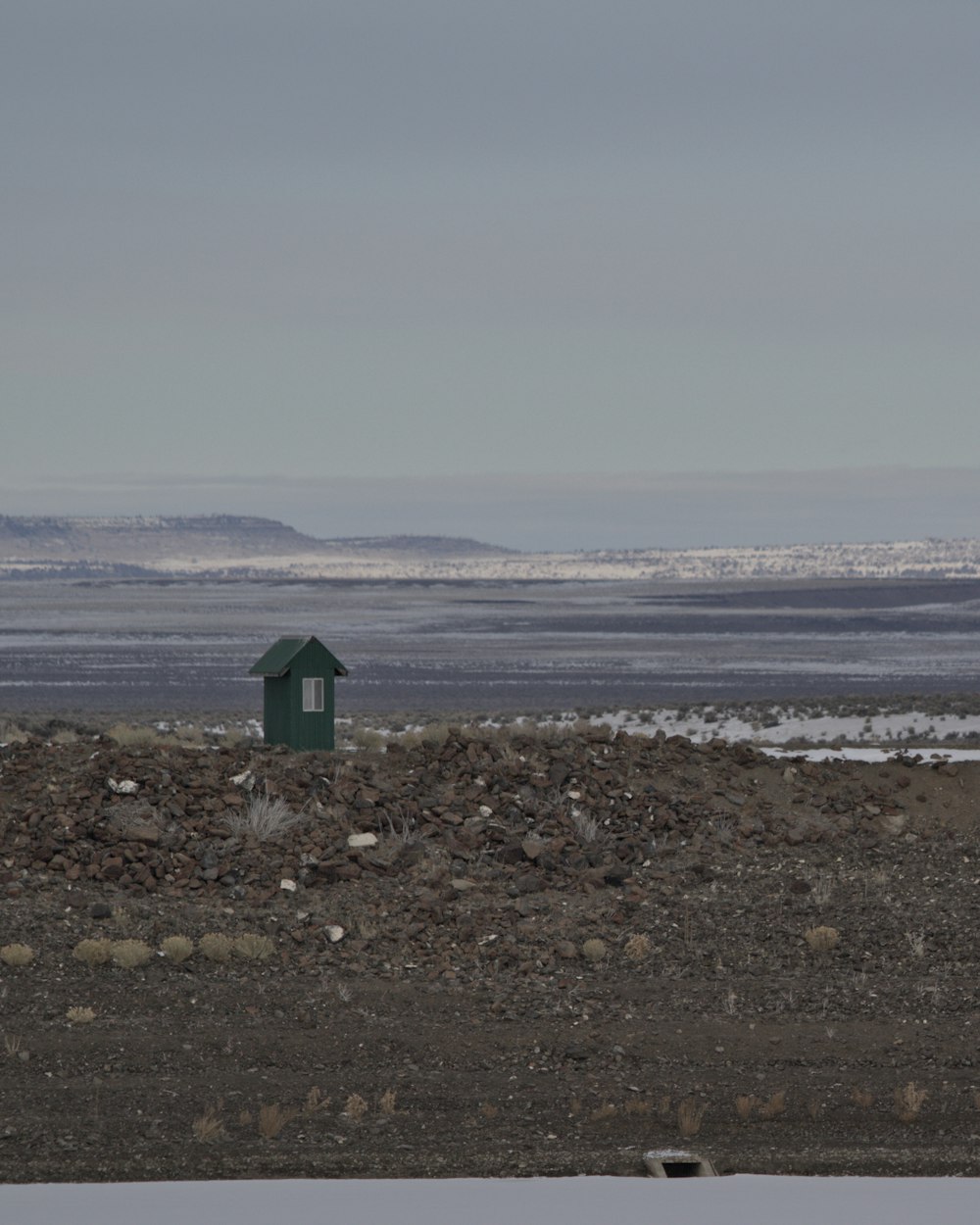 a small green building sitting on top of a rocky field