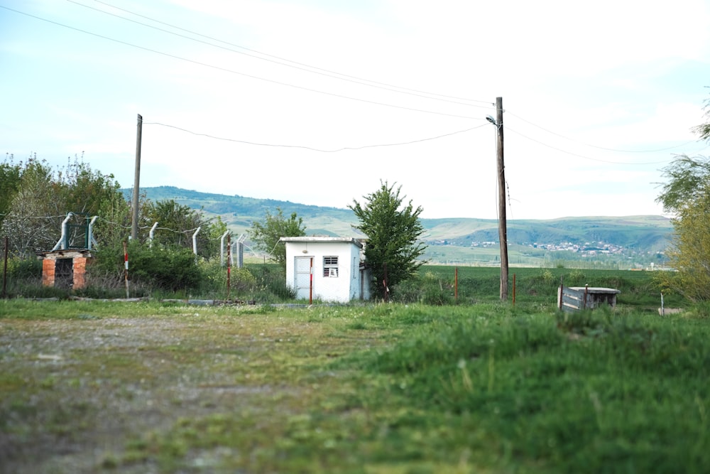 a small white building sitting in the middle of a field