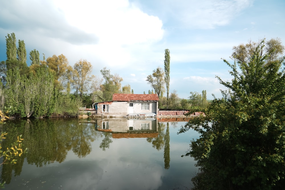 a house sitting on top of a lake next to a forest