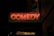 A neon sign displaying the word 'COMEDY' glows brightly against a dark background. Below this, a banner advertises 'Madagascar the Musical' with the words '2 Weeks Only' highlighted. The scene suggests a theater or comedy club setting at night.