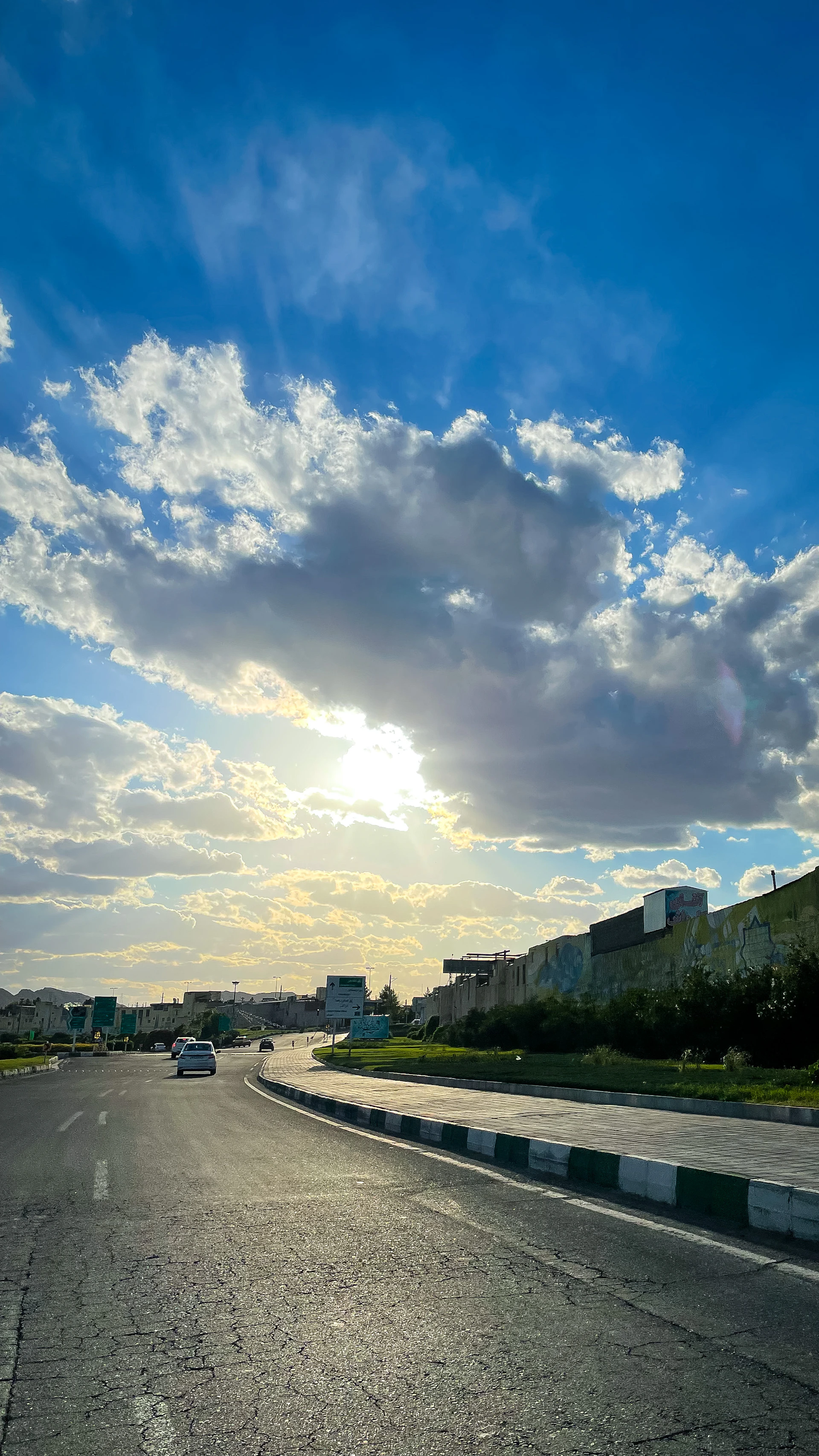A serene blue sky with soft clouds above a busy city street, symbolizing the curiosity about why the sky appears blue and everyday phenomena.