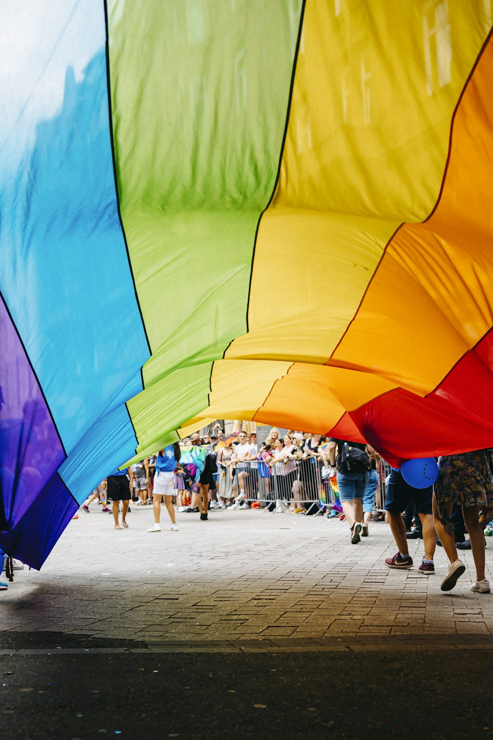 um grupo de pessoas em pé em torno de uma pipa colorida do arco-íris