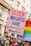 A vibrant protest sign reading 'Queer Rights Are Sexy' is held up in a crowd, with colorful and bold lettering. The background is filled with people, some wearing rainbow-themed outfits, indicating a pride or LGBTQ+ event. Nearby, another sign displays rainbow colors.