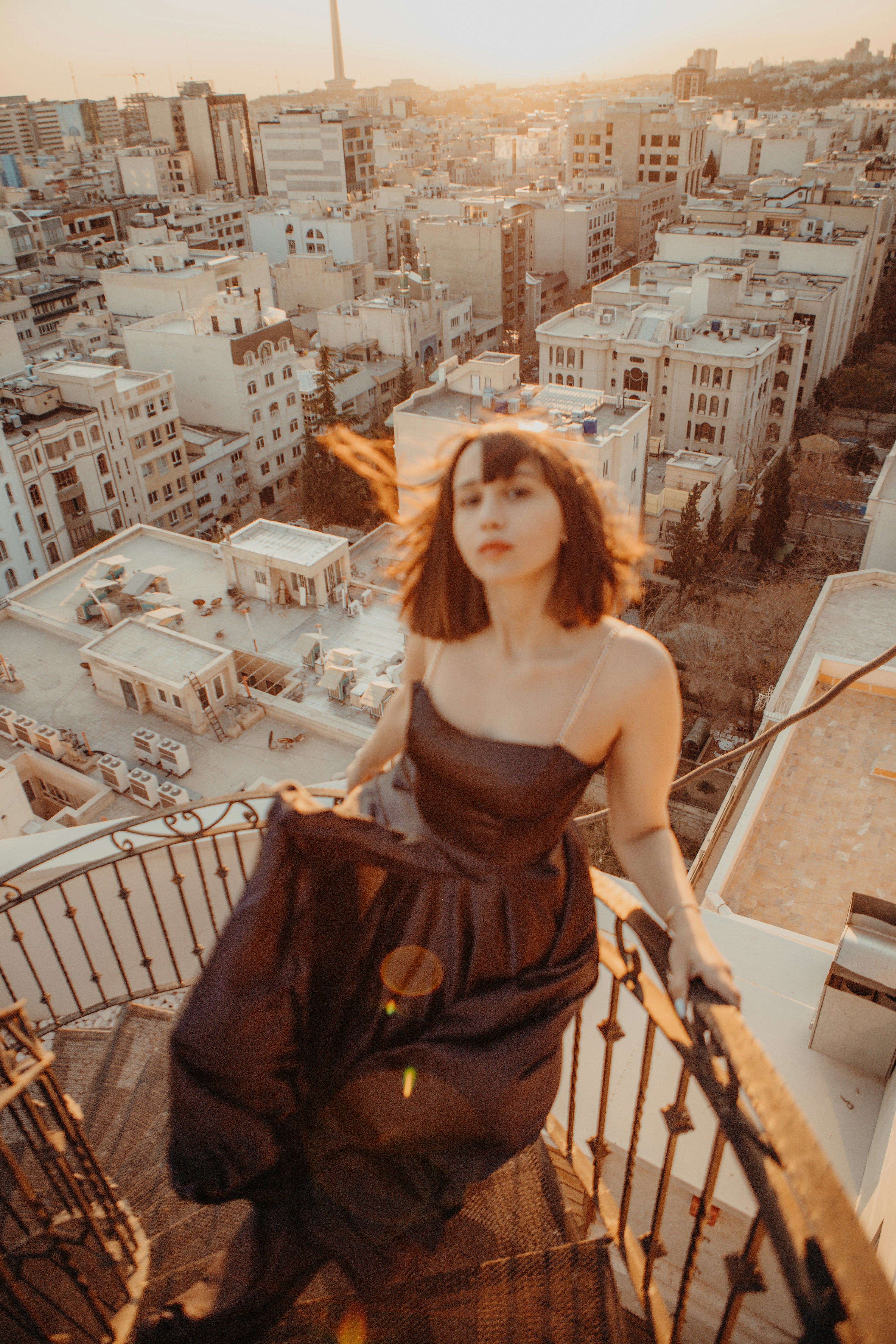 a woman in a brown dress standing on a balcony