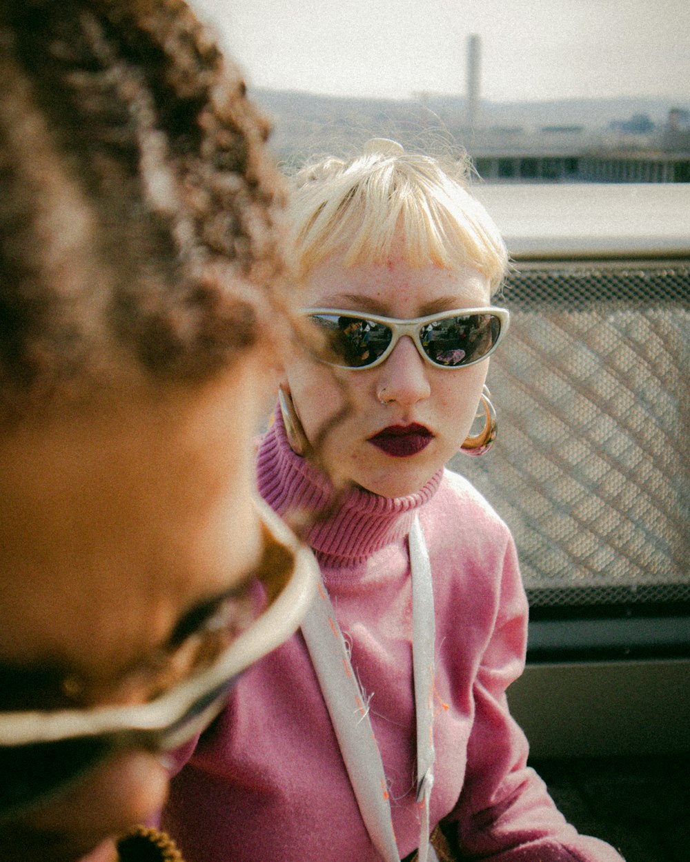 a woman wearing sunglasses and a pink sweater