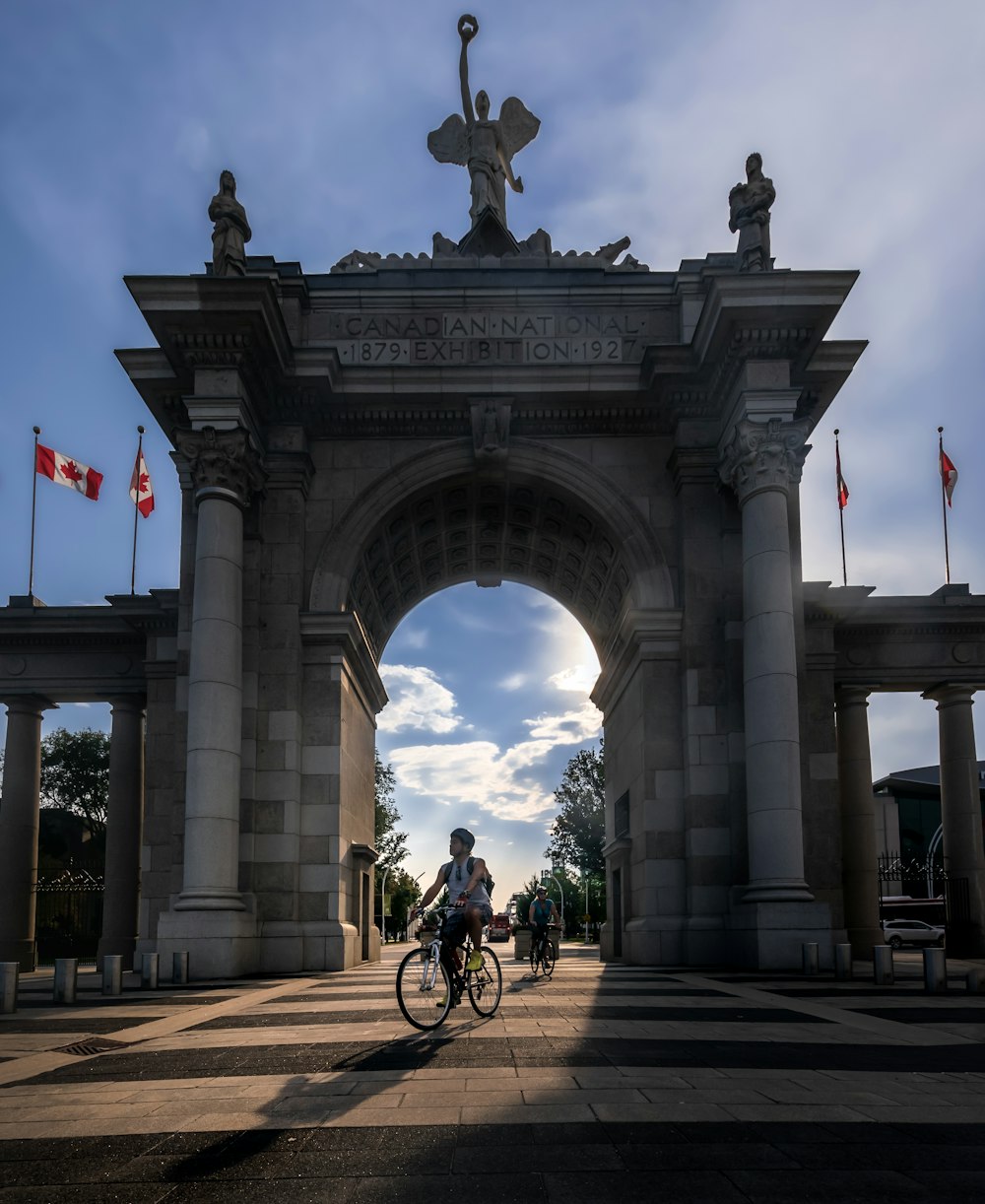 a person riding a bike in front of a stone arch