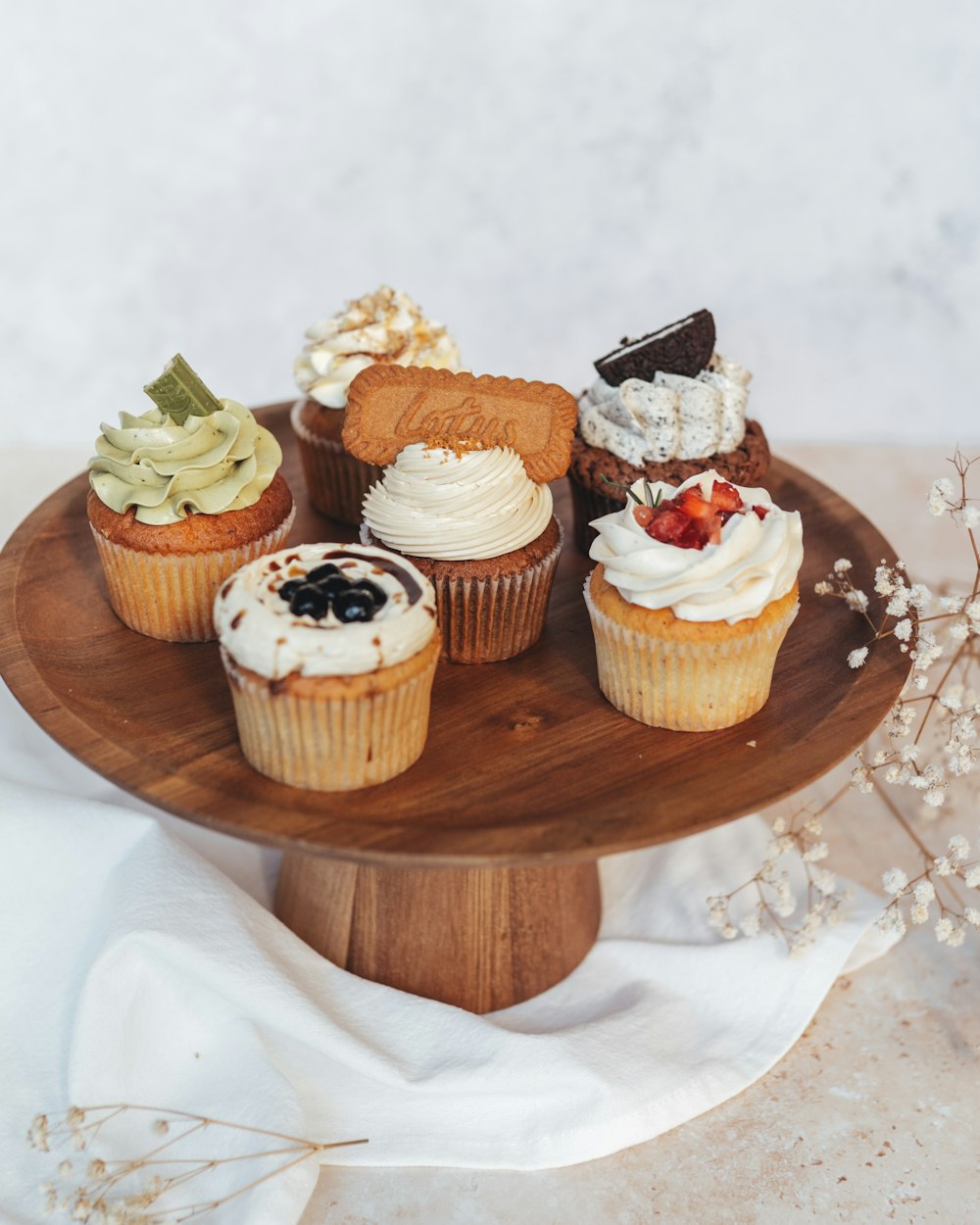a wooden plate topped with cupcakes covered in frosting