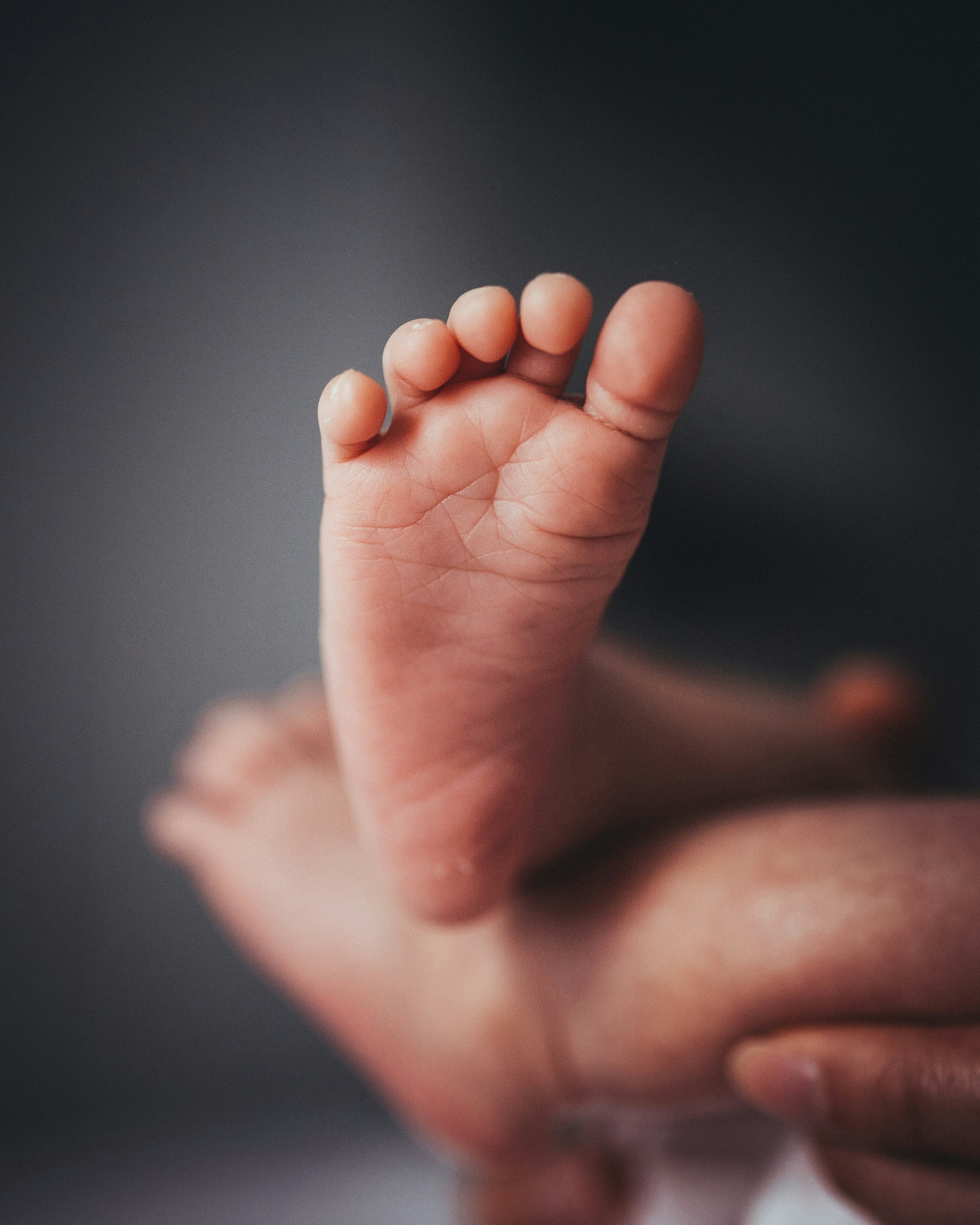 a close up of a person holding a baby's foot