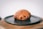 a croissant on a black plate on a wooden table