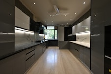 a kitchen with black and white cabinets and a ceiling fan
