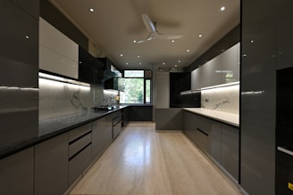 a kitchen with black and white cabinets and a ceiling fan