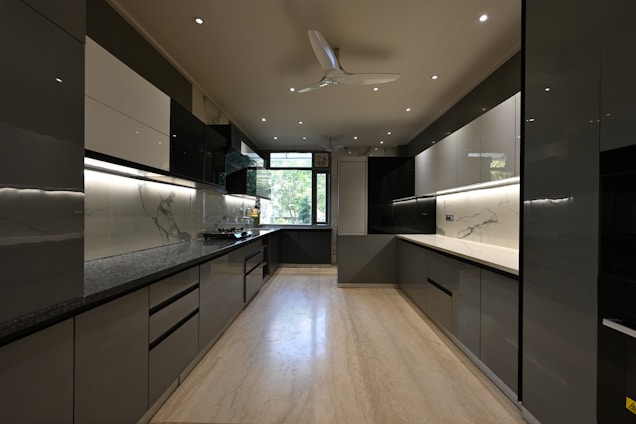 a kitchen with black and white cabinets and a ceiling fan