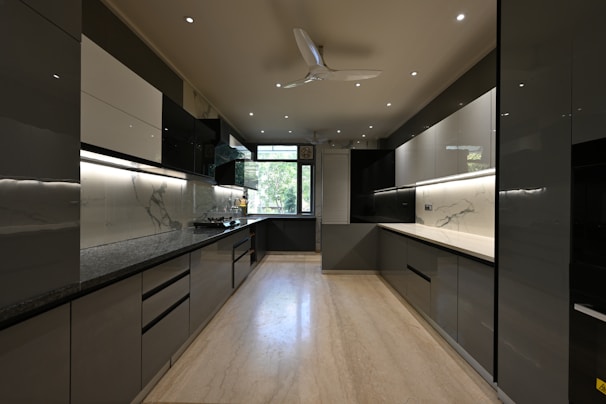 a kitchen with black and white cabinets and a ceiling fan
