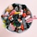 A ceramic bowl filled with a variety of colorful candies, including gummy sweets, licorice, chocolates, and sugar-coated pieces. The candies display a mix of textures, from shiny to matte and sugary surfaces.