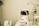 A white optometry machine is situated on an examination table, used for eye testing, alongside other medical equipment in a clinical setting. The background is neutral with smooth walls.
