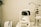 A white optometry machine is situated on an examination table, used for eye testing, alongside other medical equipment in a clinical setting. The background is neutral with smooth walls.