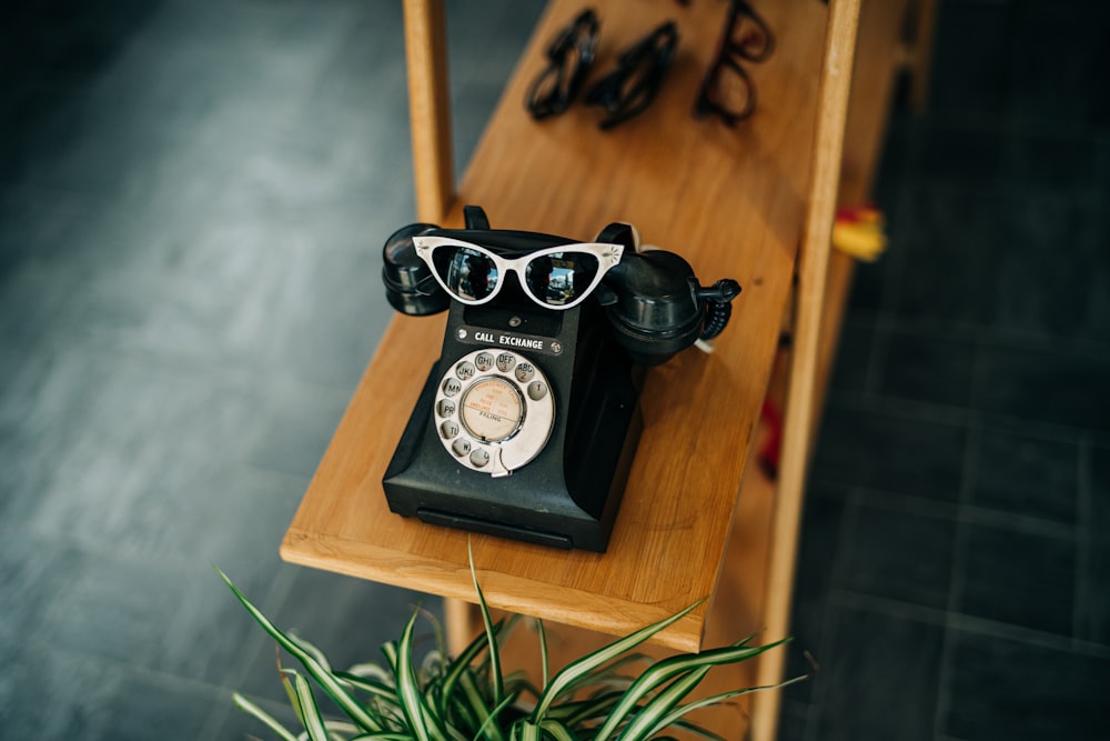 an old fashioned phone sitting on a table next to a potted plant