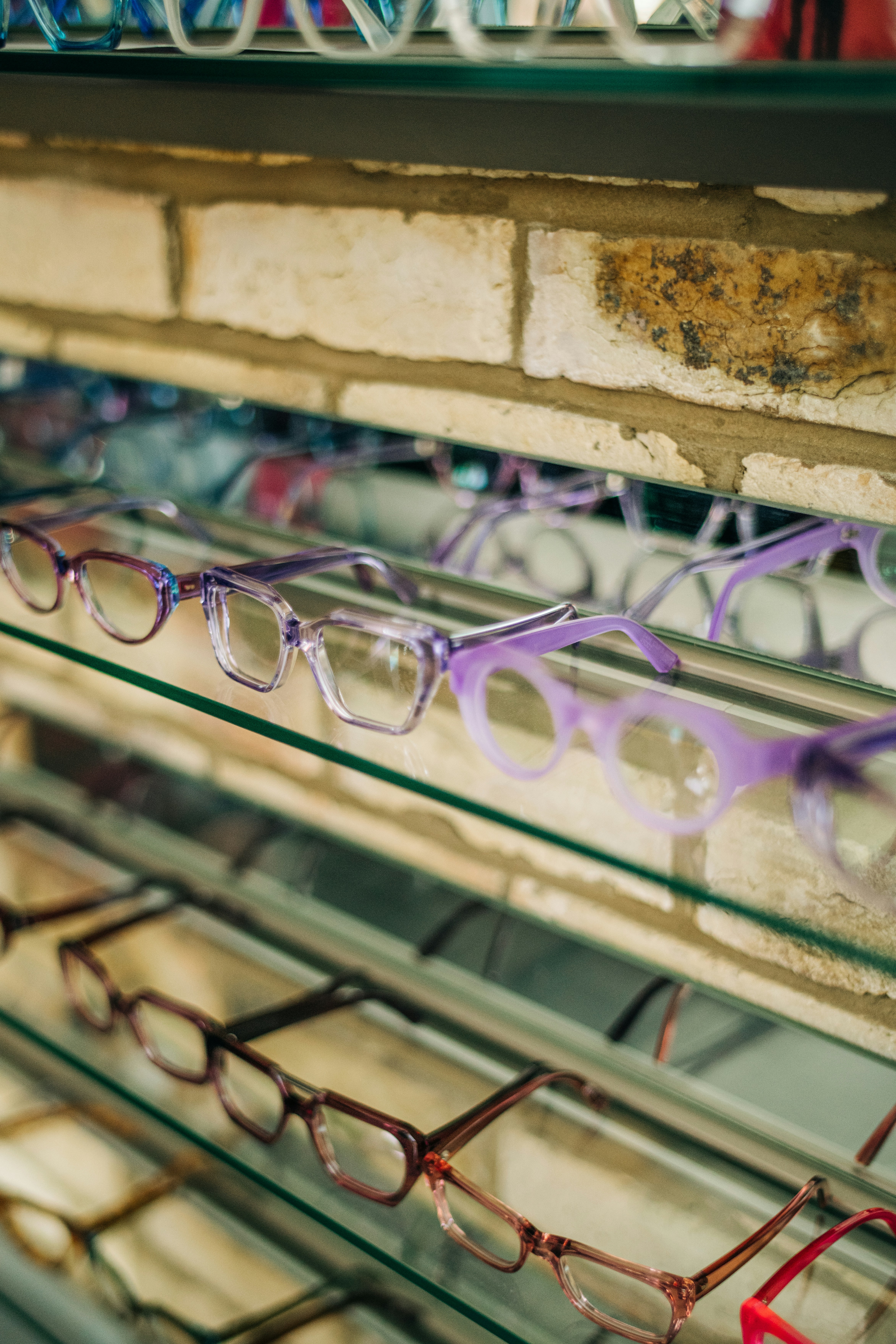 a rack of glasses in a store with a brick wall