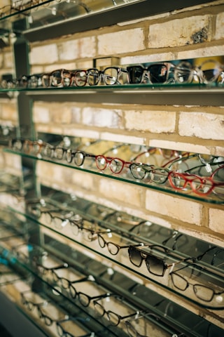 A warm, inviting optical store interior with stylish eyeglasses displayed on wooden shelves.